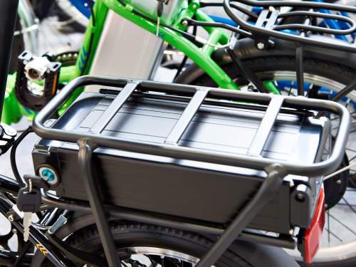 A lithium ion battery placed above the back wheel of an electric bicycle and locked in a secure metal frame with lock and key