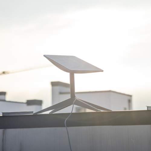 Starlink satellite receiver antenna mounted on the rooftop of a high-rise building under a clear sky